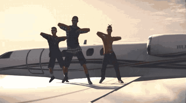 three men are dancing in front of an airplane with the letters rj on the side