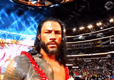 a wrestler stands in front of a stadium that says wrestlemania on it