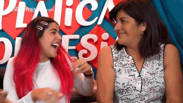 a woman with red hair laughs with another woman in front of a sign that says picnic