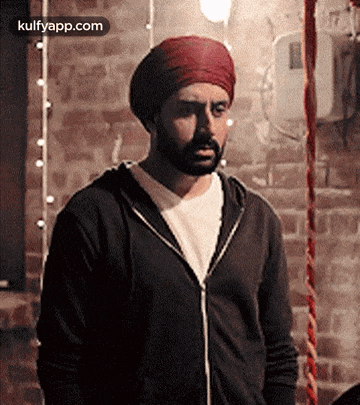 a man with a beard wearing a turban and a black jacket