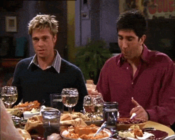 two men are sitting at a table eating food