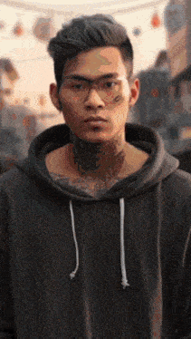 a man with a tattoo on his neck wearing glasses and a hoodie