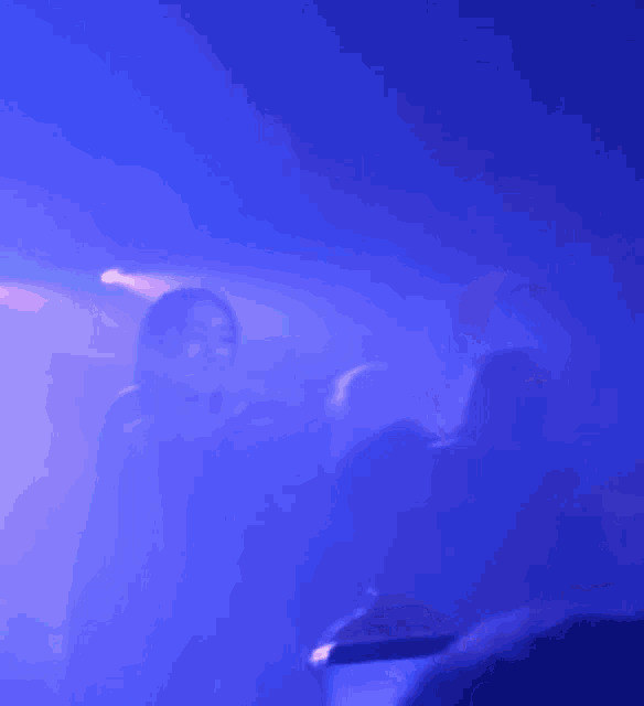 a blurry picture of a person standing on a stage with a blue light behind them