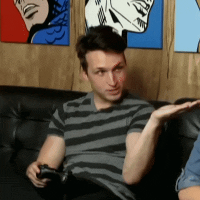a man in a striped shirt sits on a couch holding a remote control