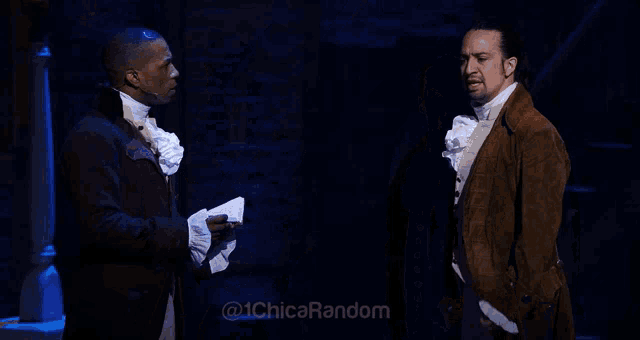 two men standing on a stage with the words @ 1chica random on the bottom right