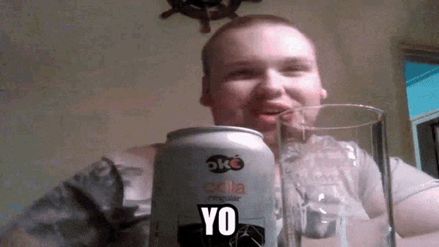 a man is holding a glass and a can of ok cola