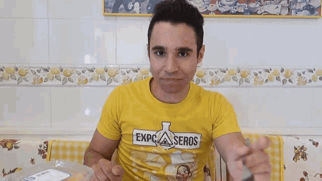 a man wearing a yellow shirt that says " exposed " is holding a fork