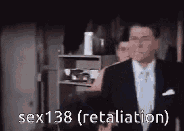 a man in a suit and tie is standing in front of a shelf with the words sex138 ( retaliation ) written on it