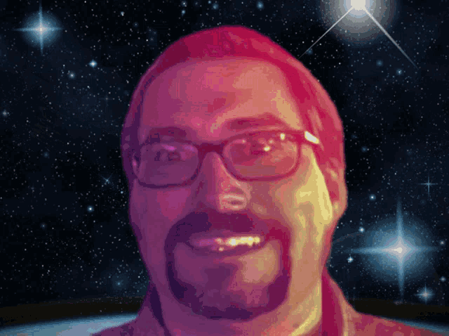 a man with glasses and a beard is smiling in front of a space background