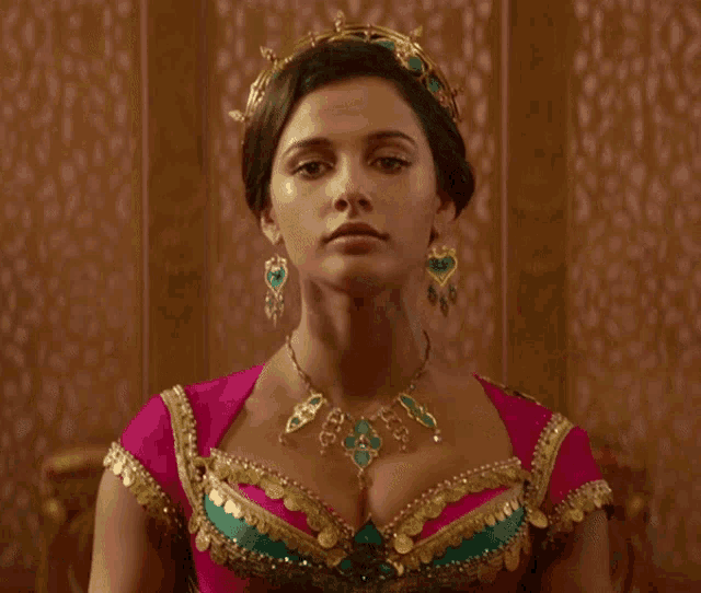 a woman in a pink and green dress with a necklace and a tiara on her head