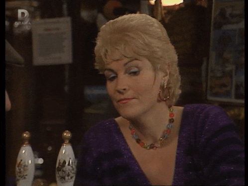 a woman in a purple dress is sitting at a table with a sign that says drama on it