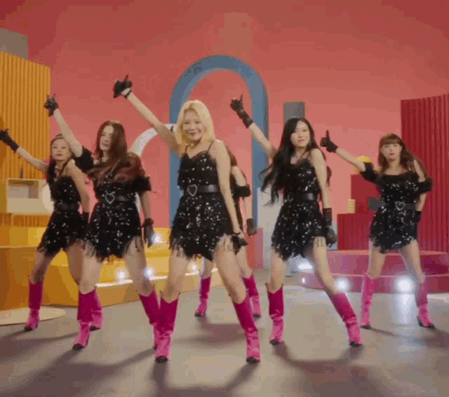 a group of girls in black dresses and pink boots are dancing together