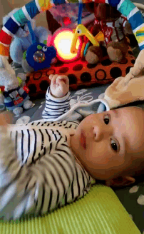 a baby in a striped shirt is laying on a mat