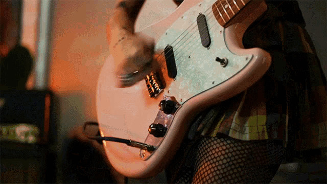 a woman in fishnet stockings is playing a pink electric guitar