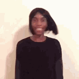 a man wearing a wig and a black sweater is smiling .