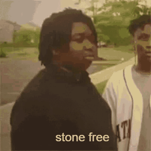 a man standing next to another man with the words stone free on the bottom