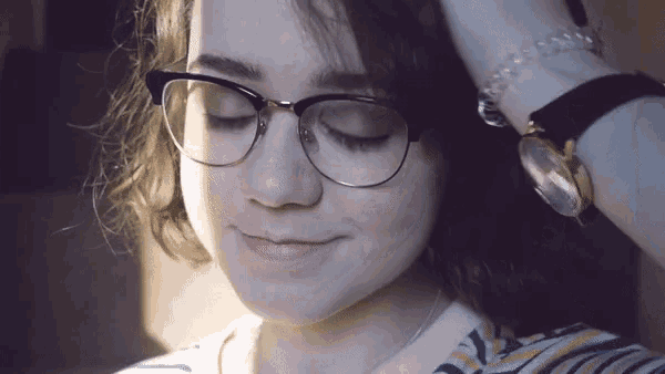 a woman wearing glasses has her eyes closed and a watch on her wrist