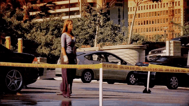 a woman stands in front of a yellow tape which says do not cross
