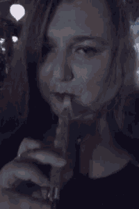 a woman is smoking a cigarette in a dark room