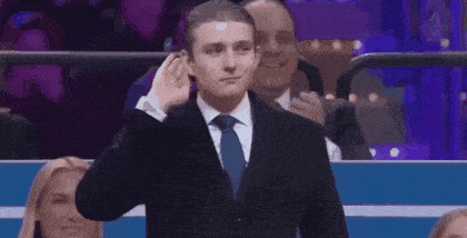a man in a suit and tie is standing in front of a crowd of people in a stadium .