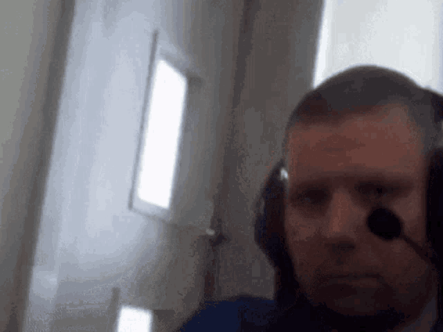 a man wearing headphones with a microphone on his head looks at the camera