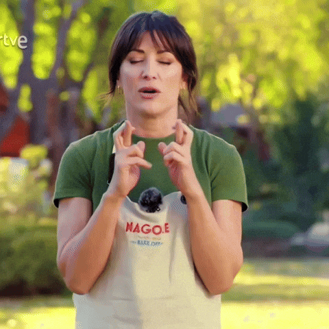 a woman crosses her fingers while wearing an apron that says nagoe on it