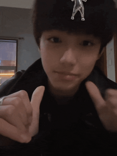 a person wearing a black jacket and a silver ring making a heart shape with their fingers