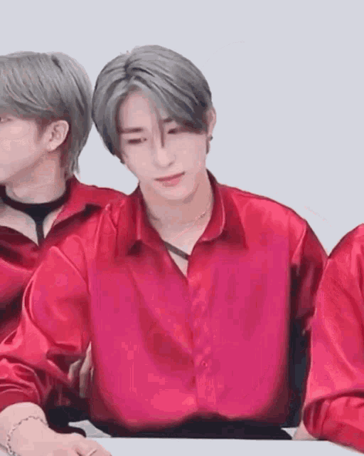 a man in a red satin shirt is sitting at a table .