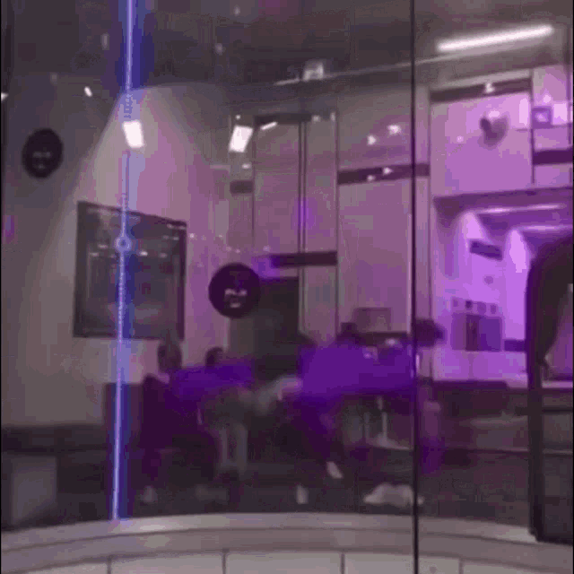 a group of people are standing in a room with a purple light behind them .