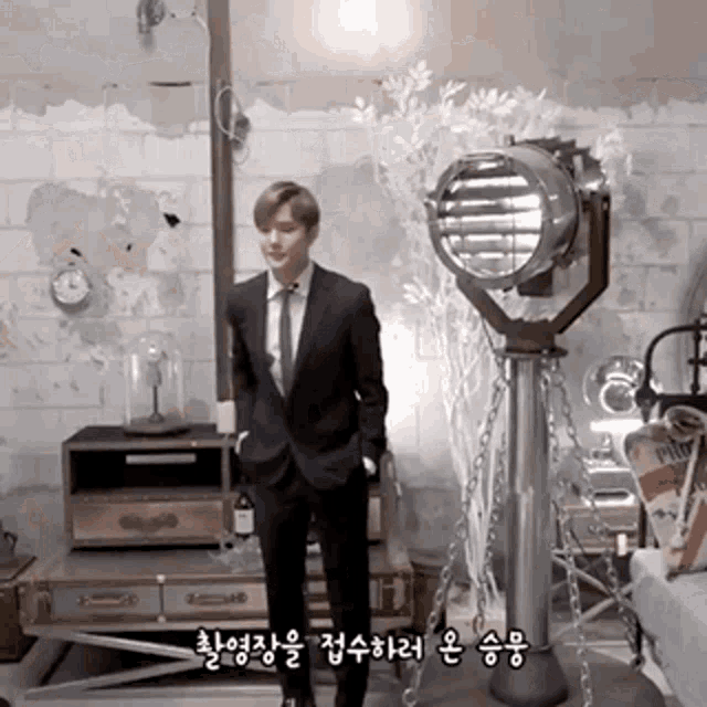 a man in a suit and tie is standing in front of a clock and a light