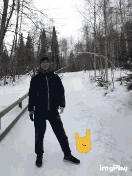a man in a black jacket stands in the snow next to a yellow sign that says heavy metal