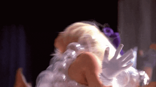 a woman in a white dress with white gloves on