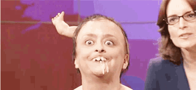 a man with a baby 's foot on his head is making a funny face .
