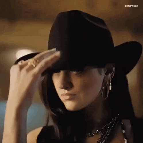 a woman is wearing a cowboy hat and earrings .