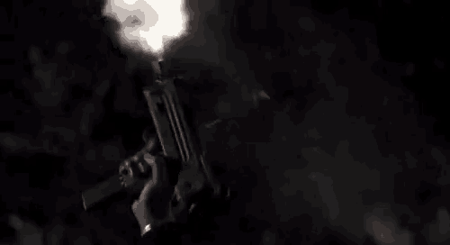a man is holding a gun with smoke coming out of it .