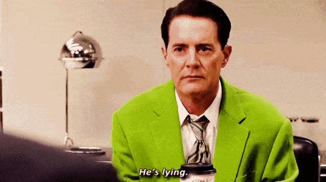 a man in a green suit and tie is holding a cup of coffee and saying he 's lying