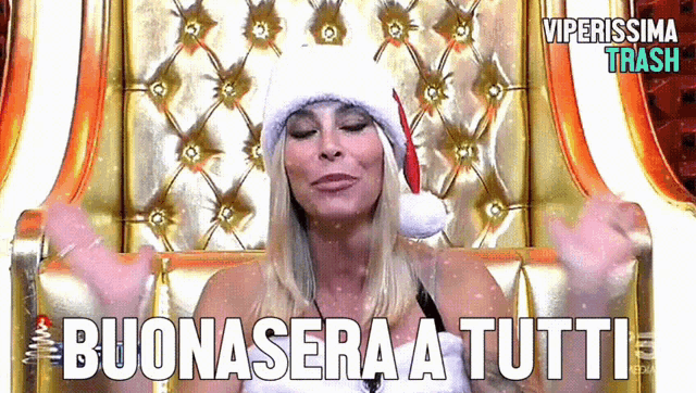 a woman wearing a santa hat is sitting in a chair with the words buonasera a tutti below her