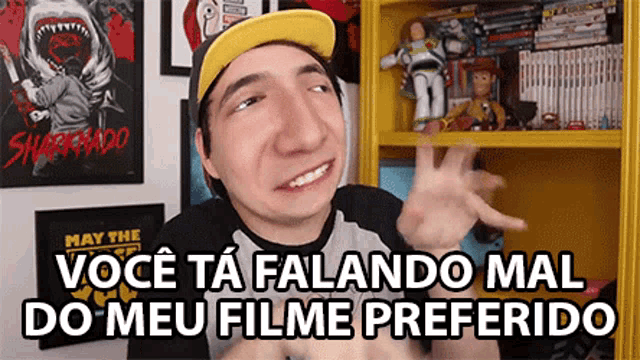 a man wearing a yellow hat is making a funny face and saying você ta falando mal do meu filme preferido