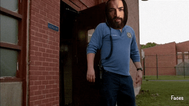 a man in a blue shirt is standing in front of a brick building with a sign on it that says ' visitor '