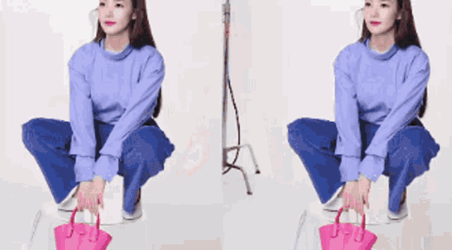 a woman in a purple sweater is squatting down holding a pink purse .