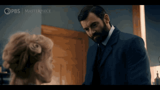 a man in a suit and tie is talking to a woman in a masterpiece ad