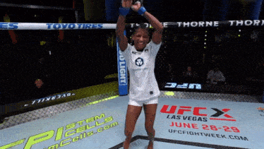 a woman in a white shirt is standing in a ufc cage