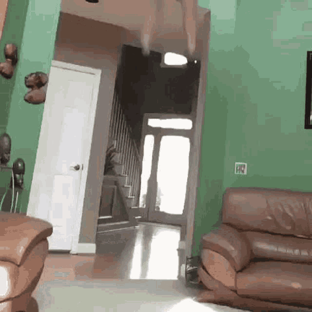 a living room with a couch and stairs and a green wall