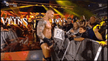 a man in a wrestling ring holds a sign that says ryc