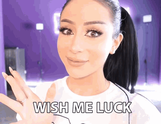 a woman wearing a white shirt that says wish me luck on it