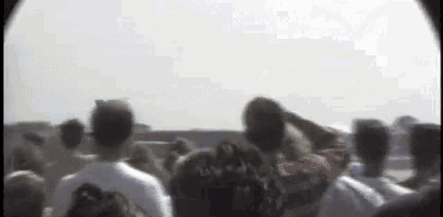 a blurry picture of a crowd of people watching a plane take off from the runway .