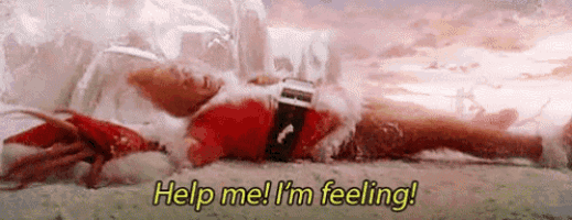 a man in a santa suit is laying on the ground in the snow .