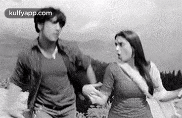 a man and a woman are standing next to each other on a hill .