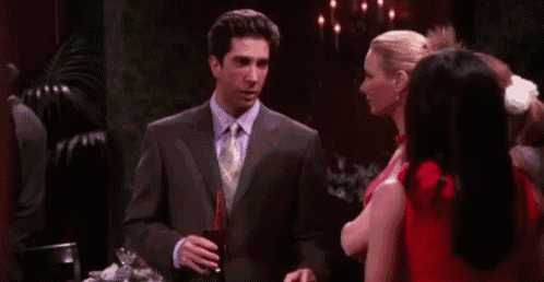 a man in a suit and tie is talking to two women in a dark room .