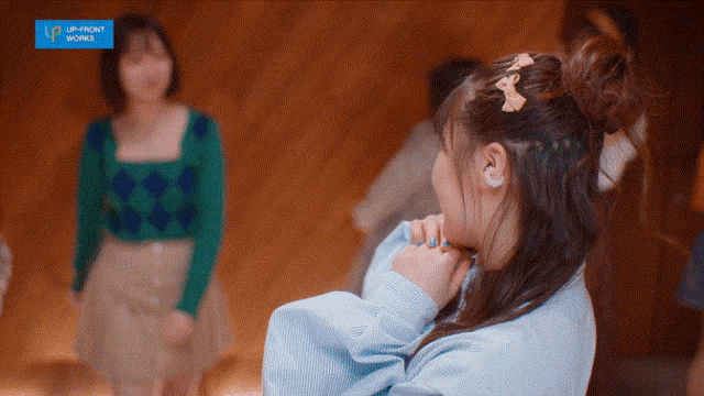 a girl in a blue sweater is standing in front of a sign that says upfront work
